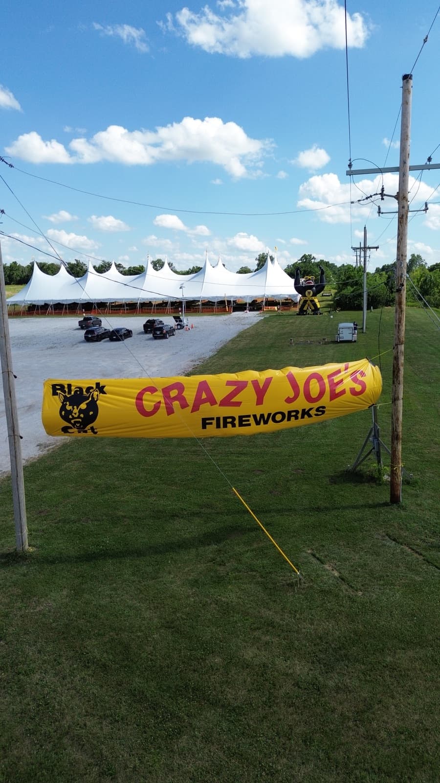The iconic Black Cat yellow Crazy Joe's Fireworks inflatable banner standing tall over the stand at 171st and Holmes in Kansas City, with the white tents in the background